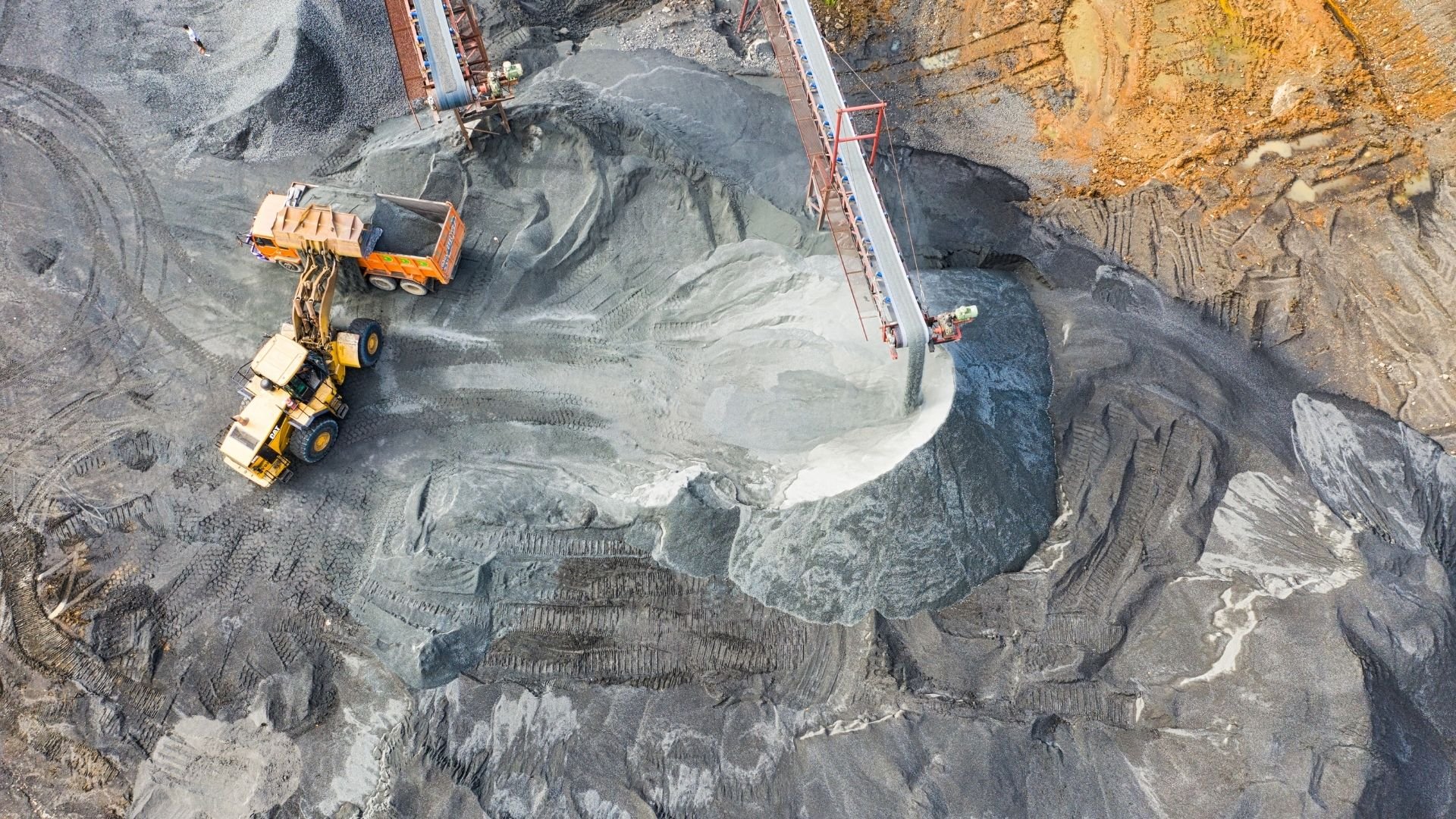 Aerial view of construction site with heavy machinery loading sand and gravel into dump truck.